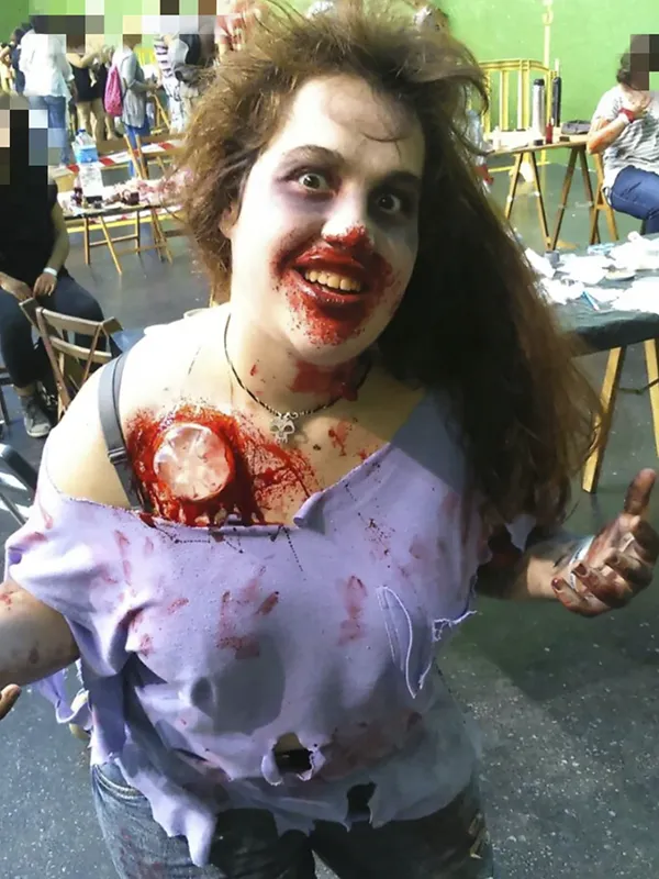 Chica joven caracterizada como zombi con maquillaje de terror para Halloween