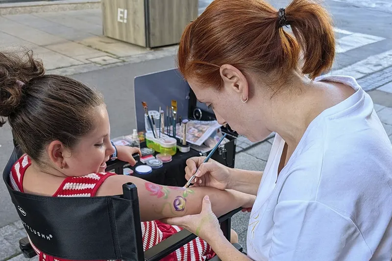 Tania Porcel realizando un diseño de pintacaras en el brazo de una niña durante un evento en fiestas de Erandio